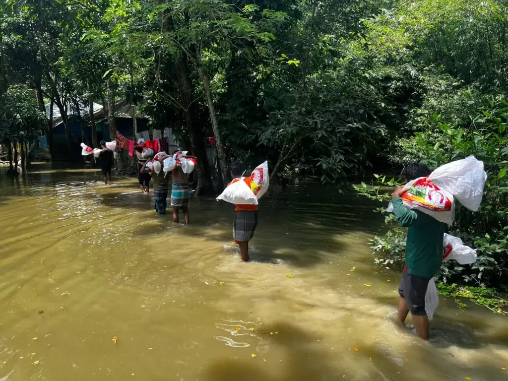 Volunteers carrying relief supplies through floodwaters to a rural community
